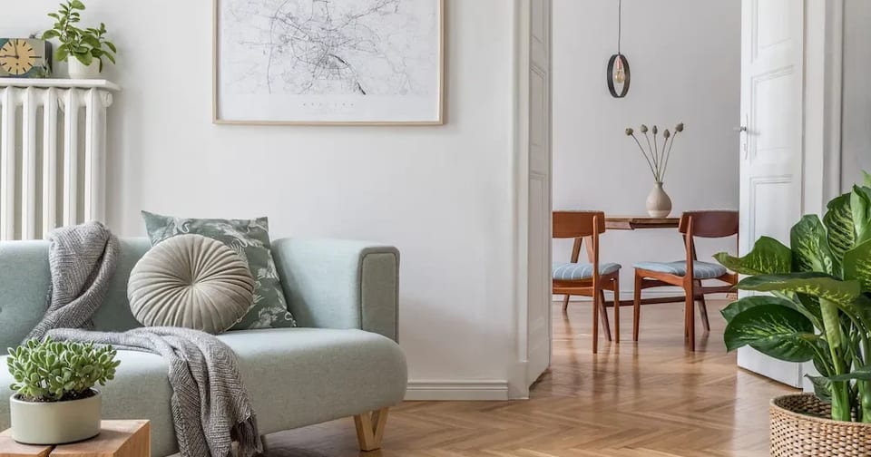 Vardagsrum med mintgrön soffa och en kartaffisch, med matplats i rummet innanför.